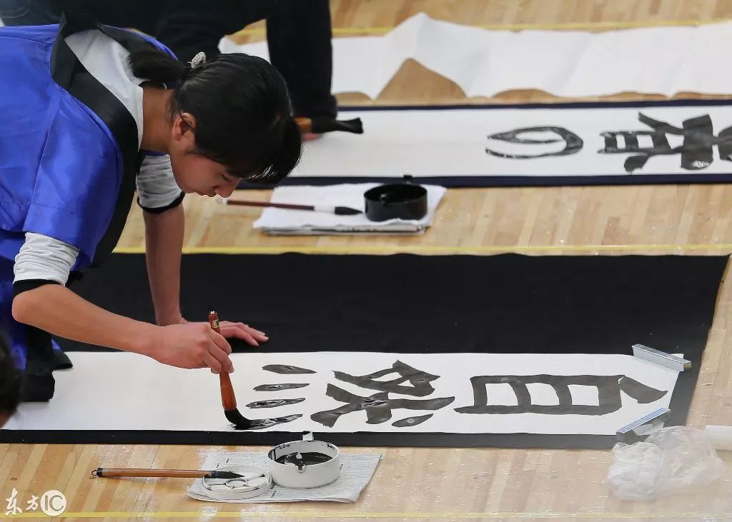日本各个年龄段的人一起使用毛笔写字,主办方希望以此展示日本的书法